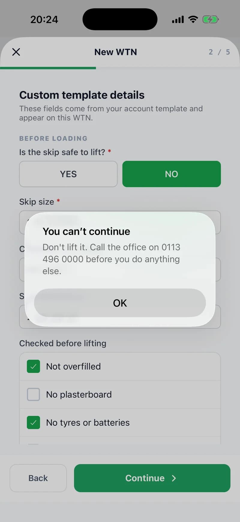 The same Details step in the app with “Is the skip safe to lift?” answered NO, and an alert on top: “You can’t continue — Don't lift it. Call the office on 0113 496 0000 before you do anything else”, with an OK button.